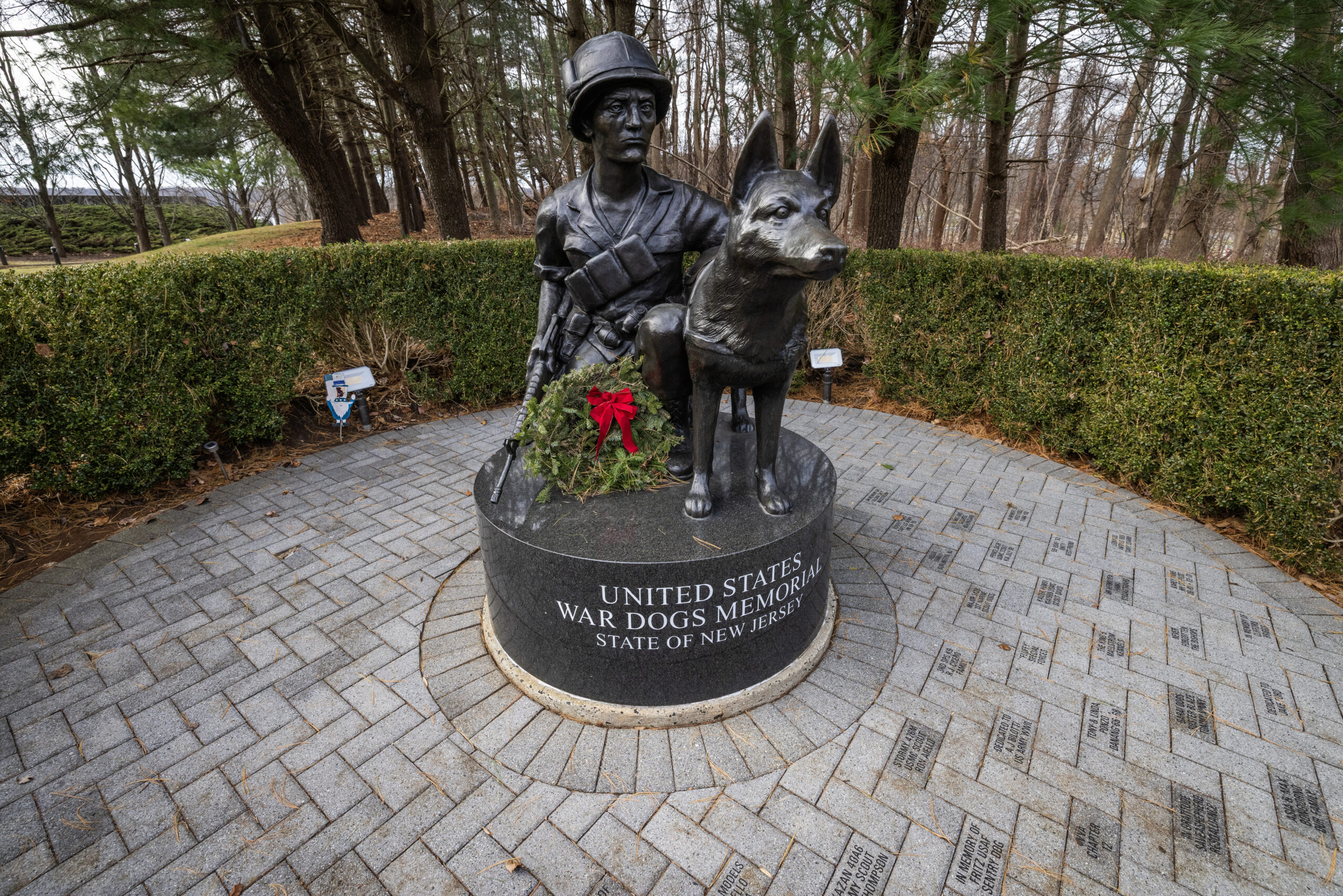 A wreath is placed at the U.S. War Dogs Memorial at the New Jersey Vietnam Veterans Memorial in Holmdel, New Jersey, Dec. 10, 2025. Wreaths were placed at the base of each of the memorial’s 366 eight-foot-tall black granite panels – each representing a day of the year – listing the names of the 1,564 New Jersey men and one woman who gave their lives while serving in Southeast Asia. In addition, the Wreaths Across America convoy stopped at the memorial on their annual journey to Arlington National Cemetery. This year marks the 50th anniversary of the end of the Vietnam War. (New Jersey Department of Military and Veterans Affairs photo by Mark C. Olsen)