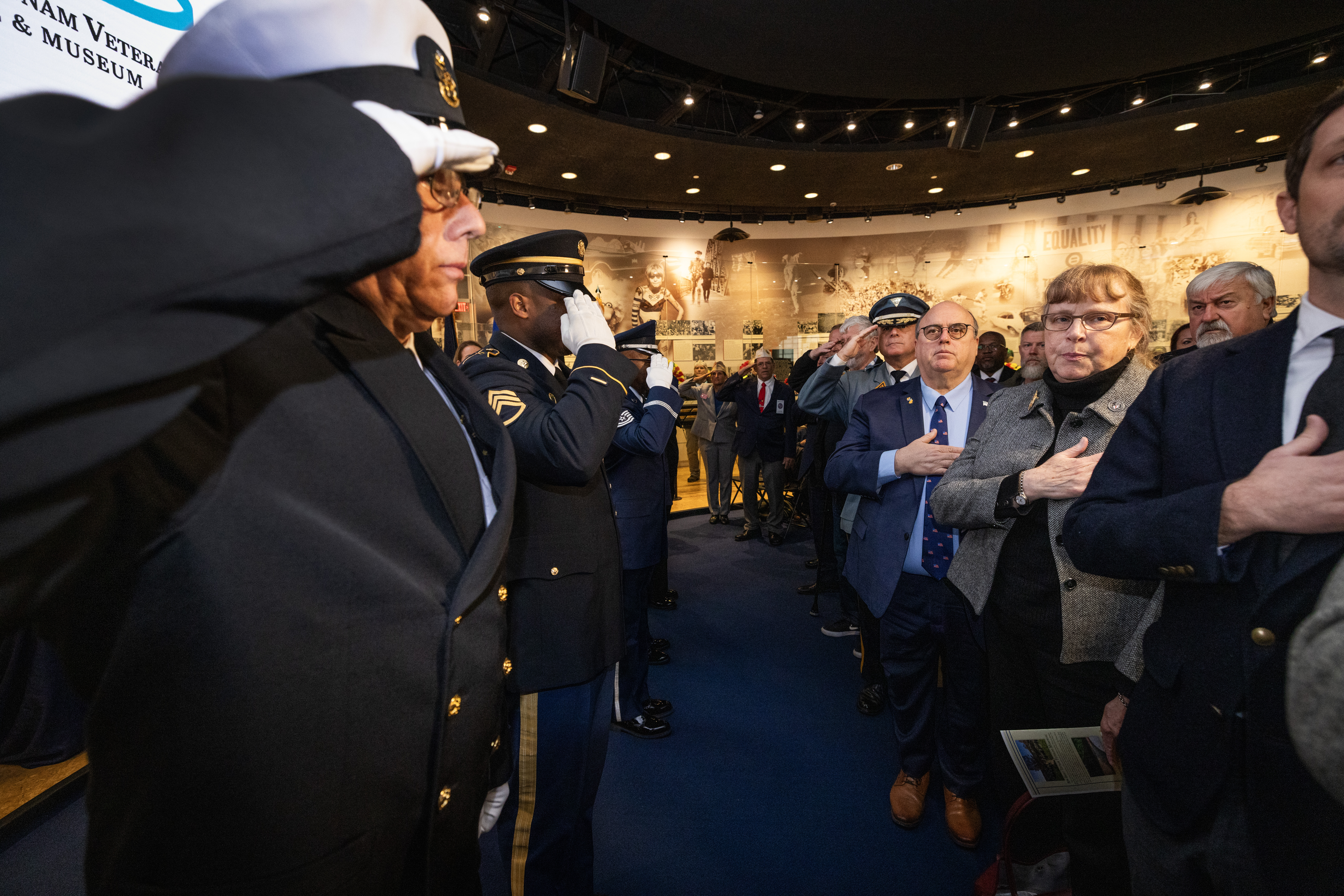 Members of the Brig. Gen. William C. Doyle Veterans memorial Cemetery Honor Guard; Veterans, family members, state and local officials render honors during the singing of the national anthem the State Veterans Day ceremony at the New Jersey Vietnam Veterans’ Memorial, Vietnam Era Museum and Educational Center at Holmdel, New Jersey, Nov. 11, 2025. Veterans Day celebrates and honors America’s veterans for their patriotism, love of country, and willingness to serve and sacrifice for the common good. (New Jersey Department of Military and Veterans Affairs photo by Mark C. Olsen)