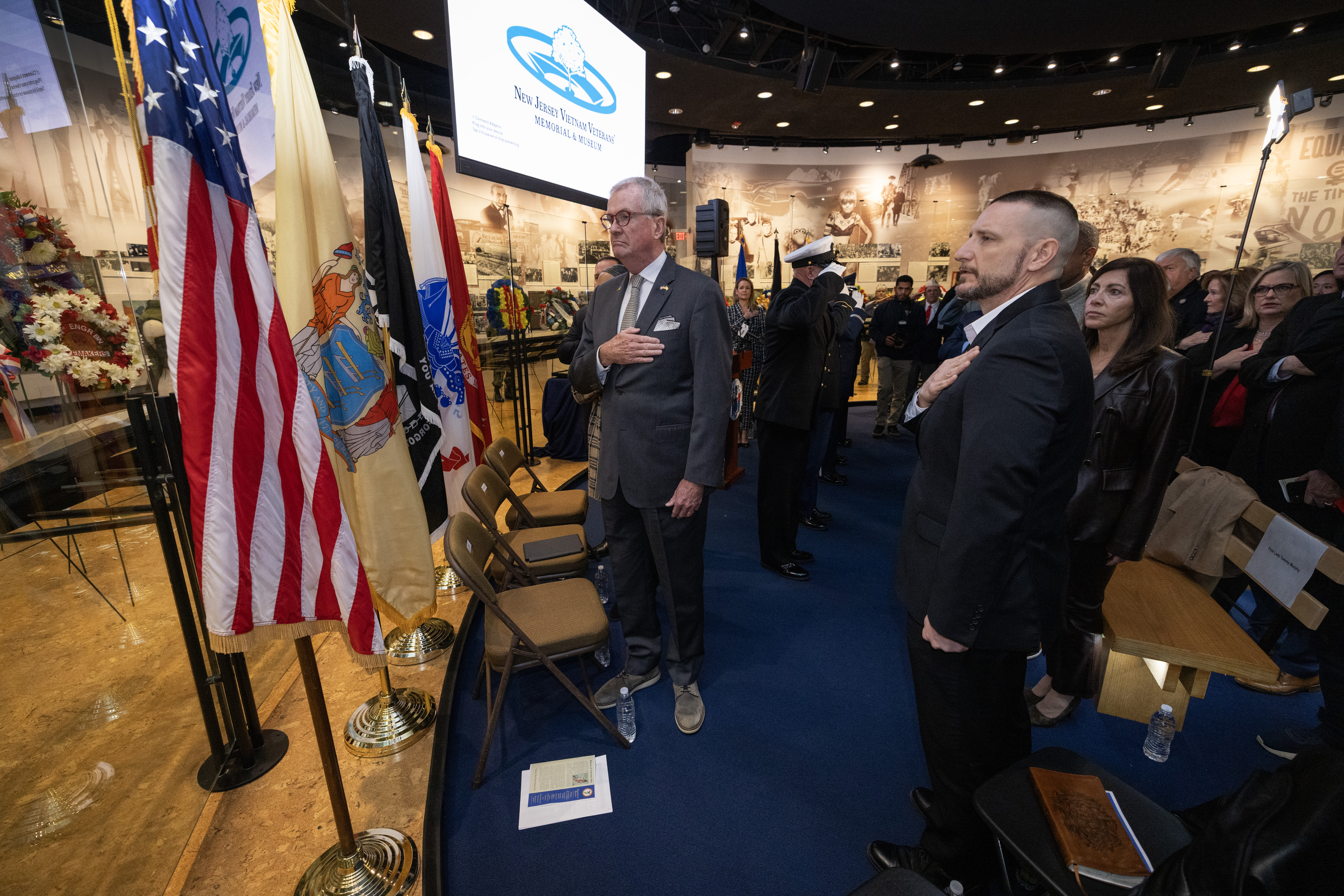 New Jersey Gov. Philip D. Murphy, Veterans, family members, state and local officials render honors during the singing of the national anthem at the State Veterans Day ceremony at the New Jersey Vietnam Veterans’ Memorial, Vietnam Era Museum and Educational Center at Holmdel, New Jersey, Nov. 11, 2025. Veterans Day celebrates and honors America’s veterans for their patriotism, love of country, and willingness to serve and sacrifice for the common good. (New Jersey Department of Military and Veterans Affairs photo by Mark C. Olsen)