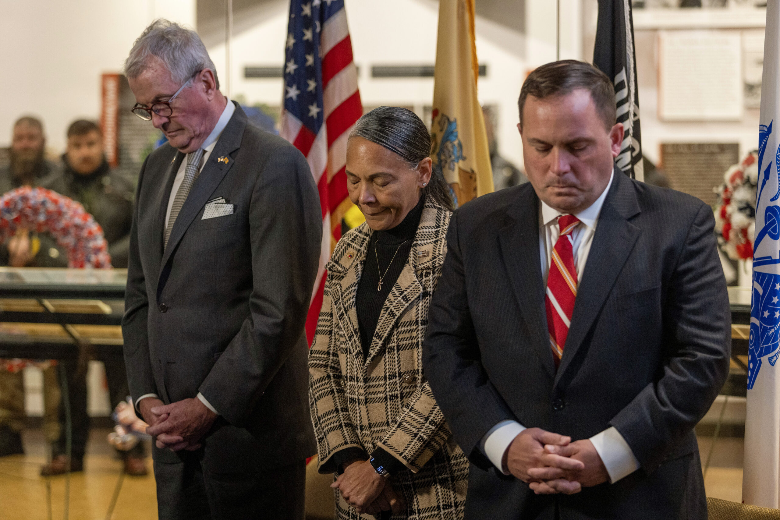 New Jersey Gov. Philip D. Murphy, left, Brig. Gen. Yvonne L. Mays, center, The Adjutant General of New Jersey, and Vincent Solomeno III, Deputy Commissioner of Veterans Affairs, New Jersey Department of Military and Veterans Affairs, and Administrator of Veterans Affairs for the State of New Jersey bow their heads during the invocation at the State Veterans Day ceremony at the New Jersey Vietnam Veterans’ Memorial, Vietnam Era Museum and Educational Center at Holmdel, New Jersey, Nov. 11, 2025. Veterans Day celebrates and honors America’s veterans for their patriotism, love of country, and willingness to serve and sacrifice for the common good. (New Jersey Department of Military and Veterans Affairs photo by Mark C. Olsen)