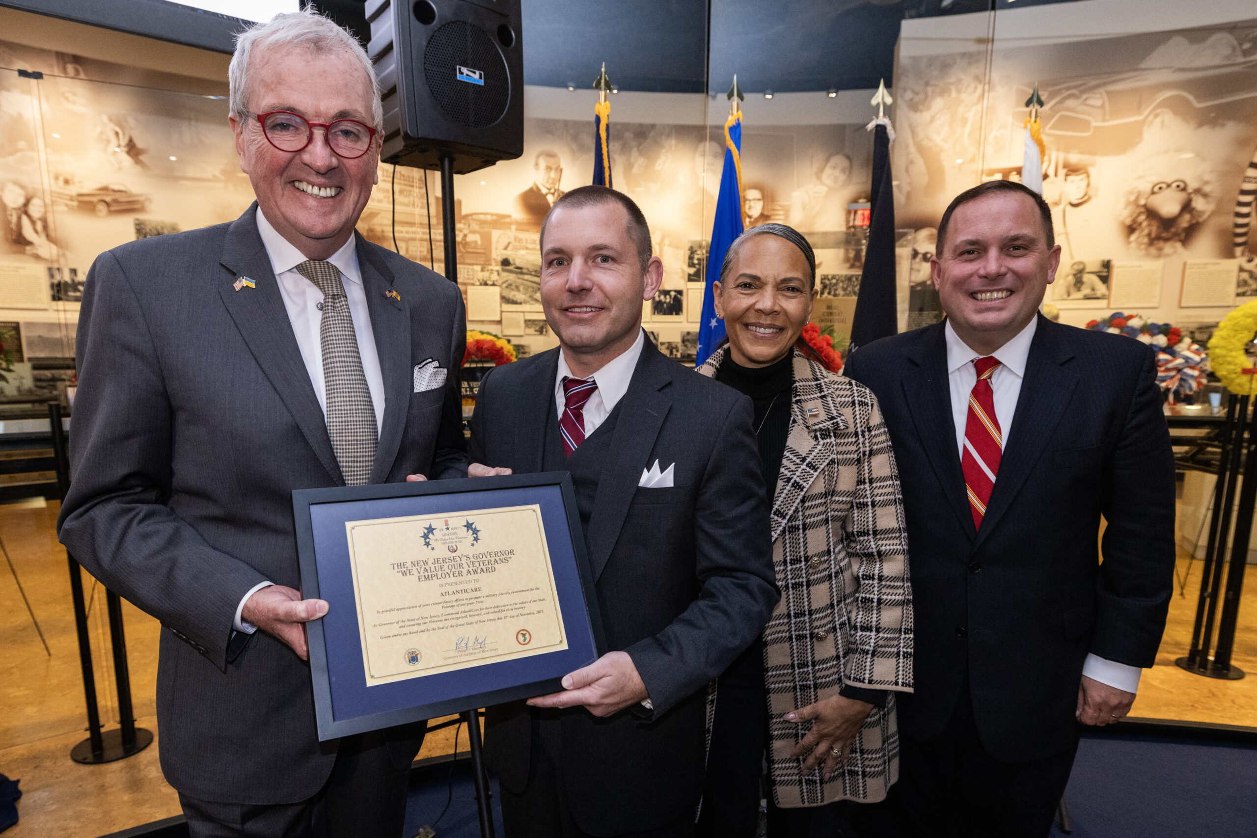 New Jersey Gov. Philip D. Murphy, left; Brig. Gen. Yvonne L. Mays, The Adjutant General of New Jersey, second from right, and Vincent Solomeno III, Deputy Commissioner of Veterans Affairs, New Jersey Department of Military and Veterans Affairs, and Administrator of Veterans Affairs for the State of New Jersey, right, present the New Jersey’s Governor “We Value Our Veterans” Employer Award to Christopher Heacock, Atlantic Healthcare Systems, second from left, during the State Veterans Day ceremony at the New Jersey Vietnam Veterans’ Memorial, Vietnam Era Museum and Educational Center at Holmdel, New Jersey, Nov. 11, 2025. The award recognizes communities, businesses, and academic institutions who honor the sacrifices, patriotism, and bravery of New Jersey’s service members. (New Jersey Department of Military and Veterans Affairs photo by Mark C. Olsen)